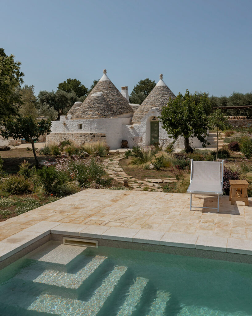 Puglia Itinerary: The Dimora Iconica trullo behind a swimming pool.