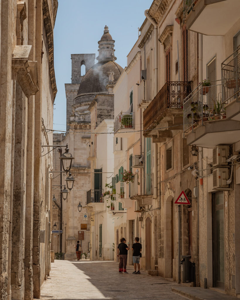 Puglia Itinerary: a street view lined with balconies and ending with a view of a dome.