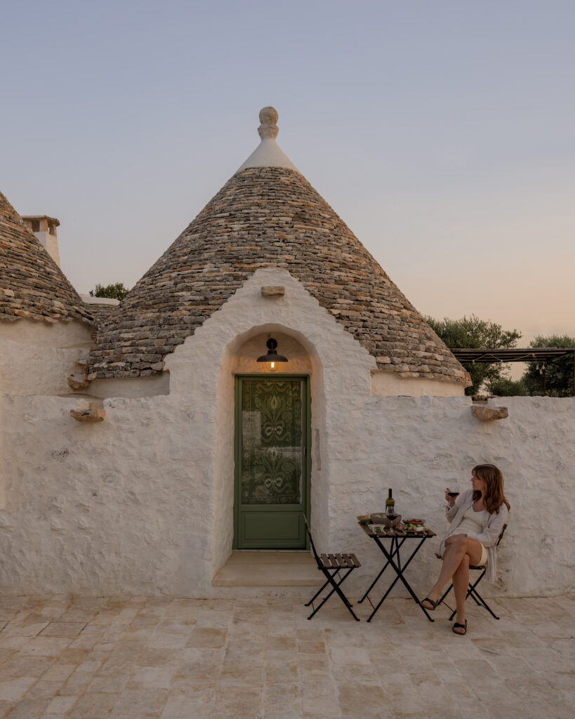 Puglia Itinerary: The Dimora Iconica trullo during sunset, with me sitting in front.