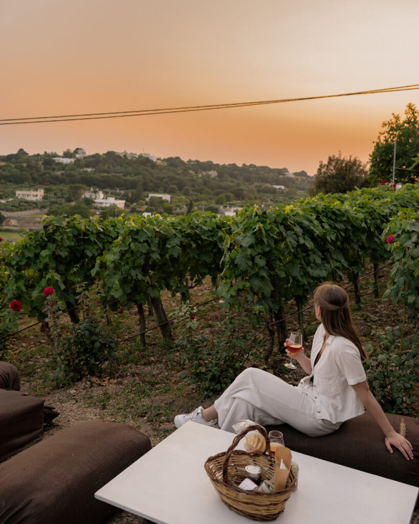 Puglia Itinerary: me sitting on a hay bale enjoying a sunset wine tasting in the vineyards at Bufano Wine.